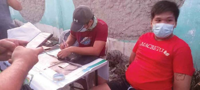 A police operative (right) is going over the items seized in a buy-bust operation in Numancia, Aklan. Seated next to him is the arrested drug suspect, Renz Lloyd Milloroso Rasgo. PHOTO BY RODNEL AGUIRRE, RMN DYKR KALIBO