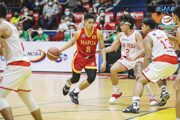 Mapua University Cardinals’ Brian Lacap dribbles the ball while being defended by three San Beda University Red Lions players. PHOTO COURTESY OF NCAA