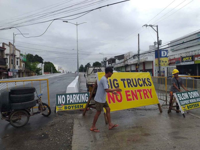 Personnel of the Department of Public Works and Highways put a huge signboard that also serves as barrier on the right side of the flyover in Barangay Ungka, Pavia, Iloilo. Only the left side of the flyover will open to traffic beginning today. ARNEL JOHN PALCULLO/PN