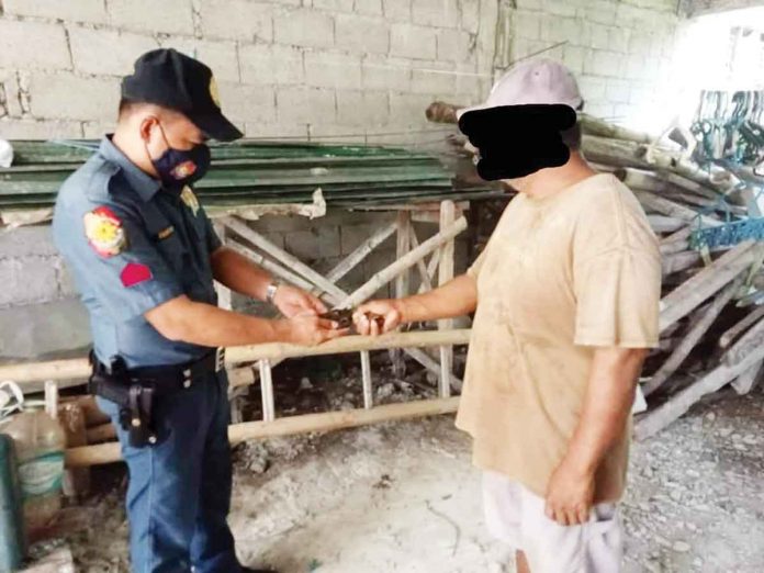 A man surrenders a homemade .38 revolver to a policeman of the Laua-an, Antique police station. LAUA-AN POLICE STATION PHOTO