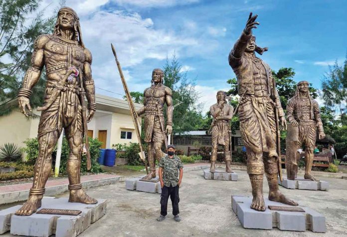 AMONG THE GIANTS. Artist John Alaban is dwarfed by his mega-size statues of Bornean datus or chieftains in this photo taken on July 13, 2022 by the Antique Provincial Tourism and Cultural Affairs Office. The statues will be installed at the Malandog Esplanade in Hamtic, Antique.