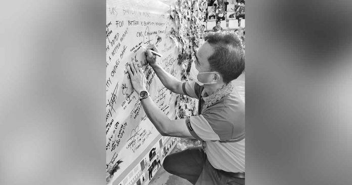 Capiz Schools Division Superintendent Dr. Miguel Mac Aposin signs a the “commitment board” during the Brigada Eskwela regional kick off in Roxas City. Aposin commits to promote the bayanihan spirit for a safer, healthier and better learning environment for learners. PHOTO BY MERLINDA BAGNATE