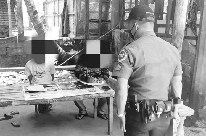 Policemen of Guimaras check the items recovered from a drug suspect in a buy-bust operation. The arrested suspect is seated on the left. JORDAN POLICE STATION PHOTO