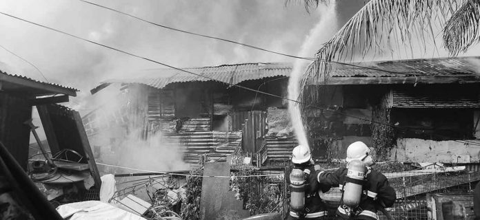 Firefighters spray water to burning houses in Barangay Villamonte, Bacolod City. BFP-BACOLOD PHOTO