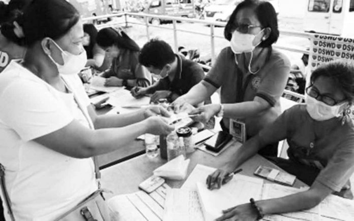 A woman receives financial assistance for her children during a payout at the Iloilo City Freedom Grandstand on Aug. 27, 2022. The educational assistance is under the Department of Social Welfare and Development’s Assistance for Individuals in Crisis Situations. DSWD-6 PHOTO