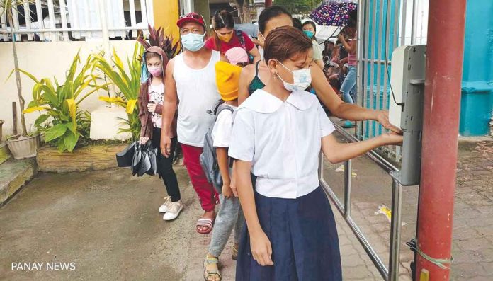 Students and parents/guardians sanitized their hands upon entering the school gate during the opening of classes on August 22, 2022. AJ PALCULLO