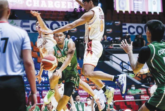 College of St. Benilde Blazers’ James Pasturan eludes two University of Perpetual Help Altas defenders to pass the ball to a teammate. NCAA PHOTO