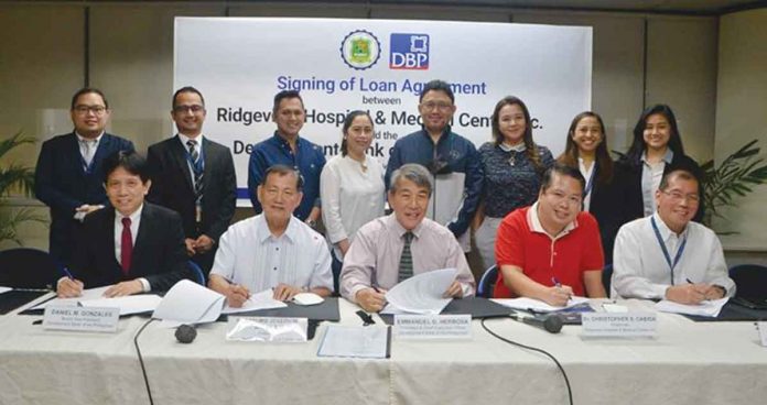 Photo shows Development Bank of the Philippines (DBP) President and Chief Executive Officer Emmanuel Herbosa (seated, third from left) with other key officials of DBP and Ridgeview Hospital and Medical Center, Inc. (RHMCI) during the signing of the memorandum of agreement between the two institutions. Seated from left are DBP Senior Vice President Daniel Gonzales; RHMCI president, Fr. Arturo Joseph Balagat; RHMCI chairman, Dr. Christopher Cabida; and DBP Executive Vice President Paul Lazaro. Standing from left are Russel Lance Ragudo of DBP; DBP Assistant Vice President Brian Niño Juniller; Dr. Jerome Idea, Dr. Jenny Lynn Idea, Dr. Cipriano Delos Reyes, and Caroline Cabida of RHMCI; and Mgr. Ana Patricia Gaviola and Christine Allaine Saporsantos of DBP.