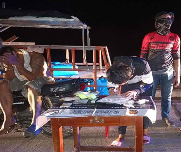 Drug suspect Kelly Castro (left) yields 130 grams of suspected shabu valued at around P884,000 during a drug buy-bust operation in Purok 6, Sitio Pantalan, Barangay Dacutan, Dumangas, Iloilo on Monday night, Nov. 21. DUMANGAS MPS PHOTO