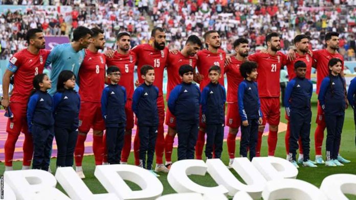 Iran players stand in silence as their national anthem play at the Khalifa International Stadium in Doha, Qatar. BBC