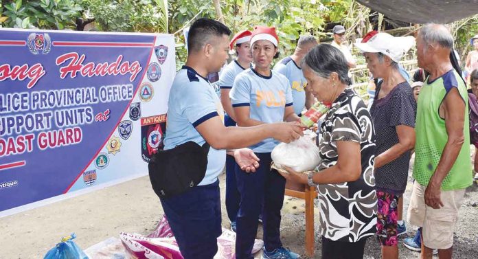 Each recipient family from Barangay Magdalena, San Remigio, Antique receives a food pack containing rice and canned goods as early Christmas gift from the Antique Police Provincial Office on Dec. 1. PCADG WESTERN VISAYAS FACEBOOK PAGE PHOTO