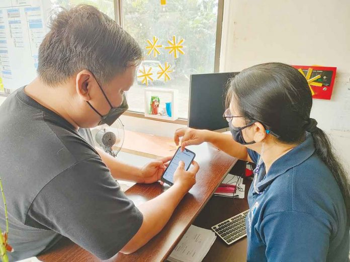 National Telecommunications Commission Region 6 administrative assistant Acela B. Bilbao (right) assists a walk-in client register his subscriber identity module (SIM) on Dec. 27 – the first day of implementation of the SIM Registration Act. AJ PALCULLO/PN