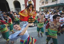 A dancer of a Dinagyang Festival 2023 contesting tribe raises a Sto. Niño image during the Dinagyang “Pamukaw” program in front of the Iloilo City Hall on Dec. 16, 2022. ILOILO CITY MAYOR’S OFFICE PHOTO