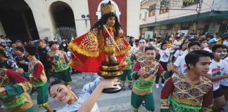 A dancer of a Dinagyang Festival 2023 contesting tribe raises a Sto. Niño image during the Dinagyang “Pamukaw” program in front of the Iloilo City Hall on Dec. 16, 2022. ILOILO CITY MAYOR’S OFFICE PHOTO