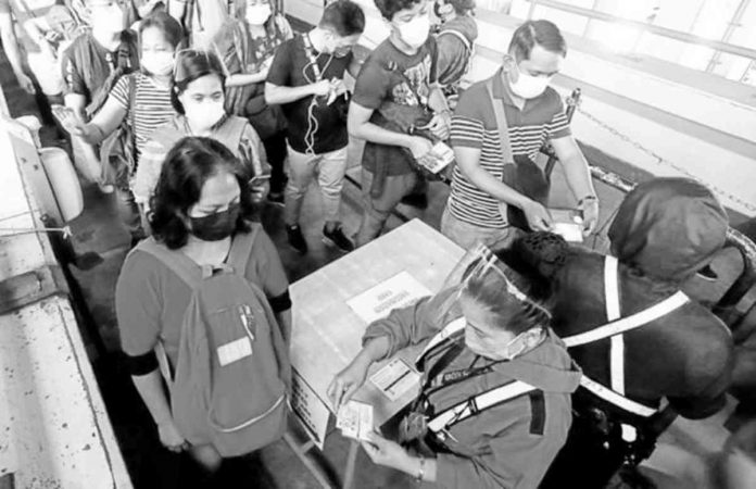 NO VAX, NO RIDE. Security guards at MRT 3, in this January 2022 photo, check vaccination and identification cards of passengers at the rail line’s North Avenue Station as the country deals with a surge in COVID-19 cases early last year. PHOTO BY NIÑO JESUS ORBETA, PHILIPPINE DAILY INQUIRER