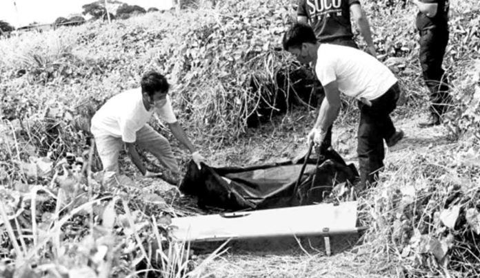 Policemen recover the body of slain hazing victim John Matthew Salilig, Adamson University student, in an open field in Imus, Cavite. PHOTO FROM CAVITE PPO