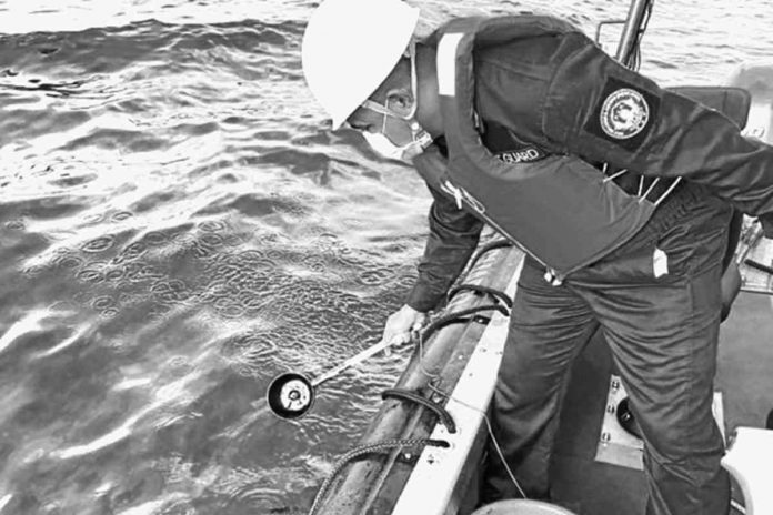 WATER SAMPLING. In this handout photo from the Philippine Coast Guard taken on March 2, 2023, a coastguard personnel collects water samples from an area hit by oil spill off the waters of Naujan, Oriental Mindoro. The spill, a mix of industrial fuel and oil, came from a tanker that sank there on Feb. 28.