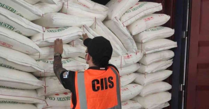 A personnel of the Customs Intelligence and Investigation Service examines sacks of smuggled sugar and onions in this undated photo. The Bureau of Customs on Sunday, March 5, said it found smuggled agricultural products worth P101.6 million in 17 shipments at the Manila International Container Port during inspections on Feb. 27 and 28. BOC PHOTO