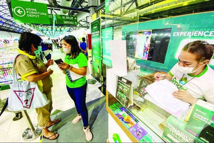 A sales representative of a telecommunications company assists clients register their prepaid subscriber identity module (SIM) cards. The registration has been extended for another 90 days or until July 25, 2023. ABS-CBN NEWS PHOTO