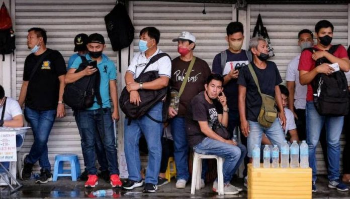 Job applicants take shelter from the rain as they line up outside the Luneta Seafarer’s Center in Manila. GEORGE CALVELO, ABS-CBN NEWS/FILE