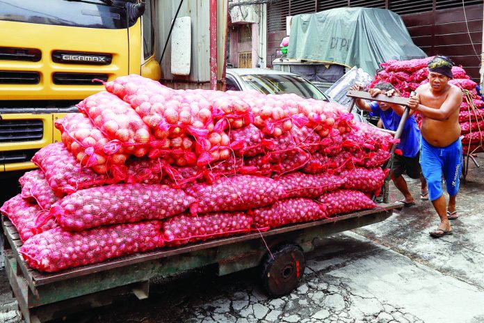 Porters push a cart loaded with onions in Binondo, Manila. The Department of Agriculture is targeting to implement and enforce the suggested retail price (SRP) on Tuesday, May 23. PNA PHOTO BY YANCY LIM