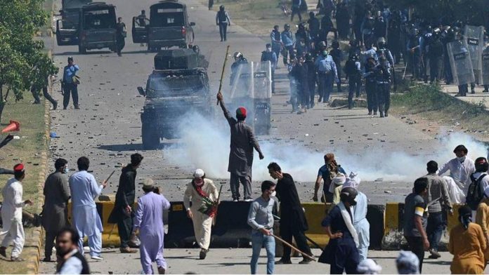 Police use teargas to disperse Pakistan Tehreek-e-Insaf (PTI) party activists and supporters (foreground) of former Pakistan's Prime Minister Imran Khan during a protest against the arrest of their leader, in Islamabad on May 10, 2023. GETTY IMAGES