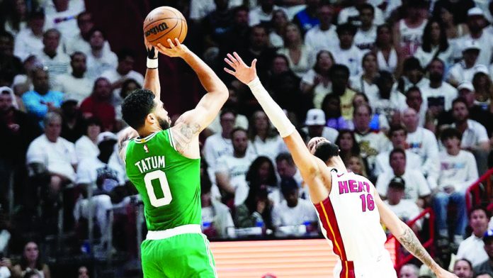 Boston Celtics’ Jason Tatum (left) concentrates on making a shot despite the distraction. AP