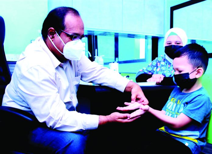 A doctor examines a child infected with hand-foot-and-mouth disease characterized by sores in the mouth and a rash on the hands and feet. It is a common infection in children. MASRY CHE ANI/THESUN PHOTO