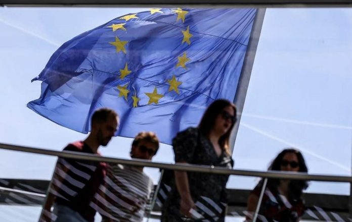 The European Union flag flies in the wind as visitors pass by at the observatory dome of the Reichstag in Berlin, Germany, May 19, 2022. OMER MESSINGER, EPA-EFE/FILE