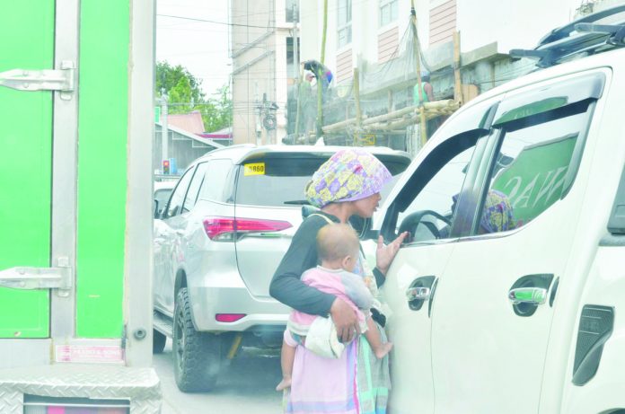 Cradling her child, a Badjao mother is asking for alms from motorists in Iloilo City. The city’s Public Safety and Transportation Management Office and City Social Welfare and Development Office are rounding up Badjaos. PN PHOTO