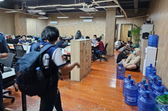 In this handout photo provided by the Philippine National Police Anti-Cybercrime Group, police walks inside one of the offices they raided in Las Piñas City, Metro Manila on Tuesday, June 27, 2023. PHILIPPINE NATIONAL POLICE ANTI-CYBERCRIME GROUP VIA AP