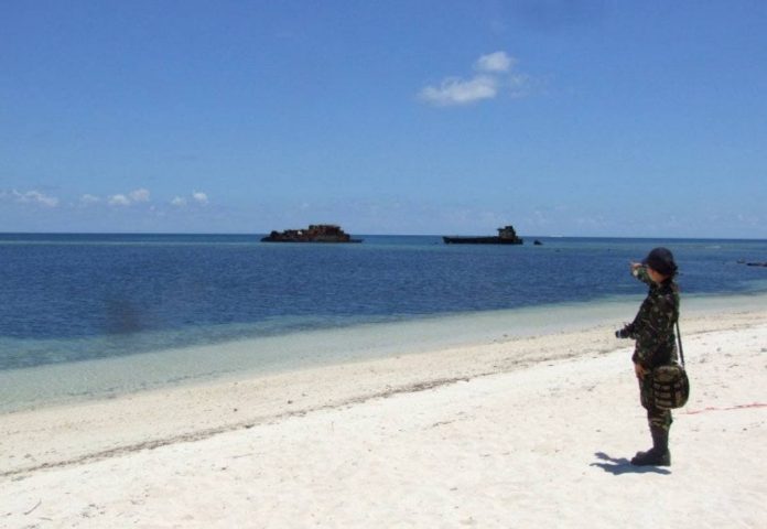 In this photograph taken in June 2014, a military officer stands on the beach on Pag-asa Island, which hosts a small Filipino town and an airstrip used for civilian and military flights in the disputed Spratly Islands in the South China Sea. AFP FILE PHOTO