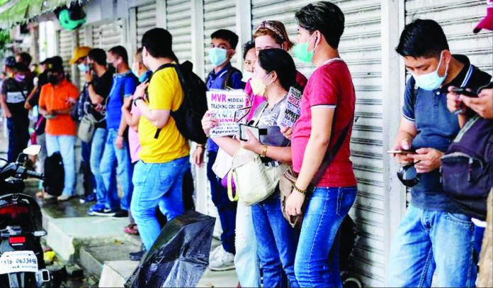 Job applicants take shelter from the rain as they line up outside the Luneta Seafarer’s Center in Manila. GEORGE CALVELO/ABS-CBN NEWS FILE PHOTO