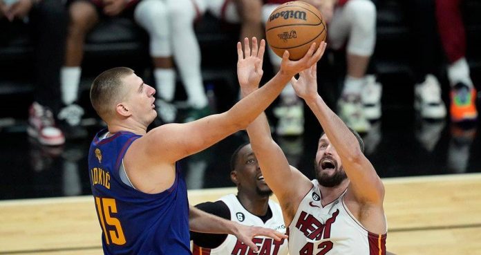 Denver Nuggets’ Nikola Jokic (left) secures the ball from Miami Heat rivals. AP