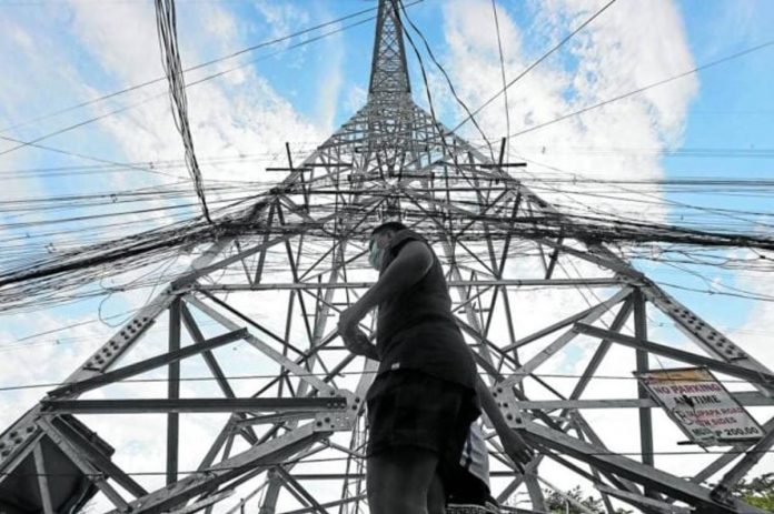 A pedestrian walks past a transmission tower of the National Grid Corp. of the Philippines. INQUIRER FILE PHOTO