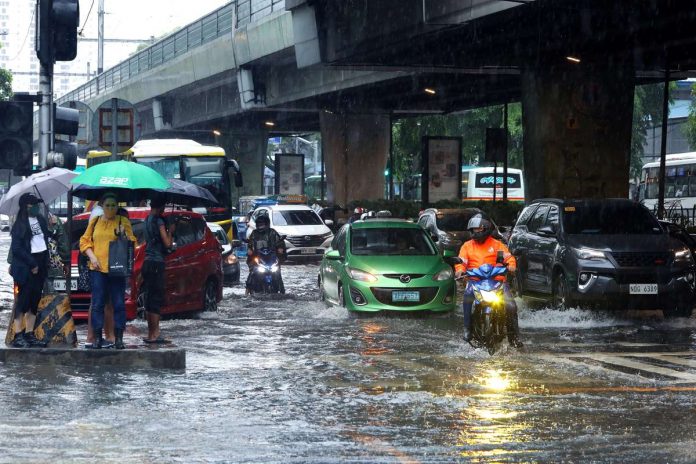 WET JOURNEY. Commuters are stranded at the center island as motorists ply through gutter-deep flood along Taft Avenue in Manila. The state weather bureau said southwest monsoon would dampen most parts of the country. PNA