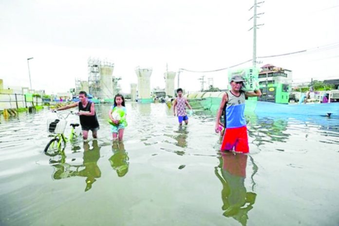 MORE FLOODS. Residents in Marilao town in Bulacan province wade through its flooded streets near pillars for the overhead MRT 7 rail line on Saturday. The weather bureau warns of more rains in the coming days from Tropical Storm “Falcon” (international name: Khanun), which is now east of Luzon over the Philippine Sea. PHOTO BY LYN RILLON / PHILIPPINE DAILY INQUIRER