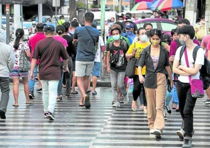 Pedestrians, many of them wearing face masks, cross Kamuning Road in Quezon City in this file photo. File photo by GRIG C. MONTEGRANDE / Philippine Daily Inquirer