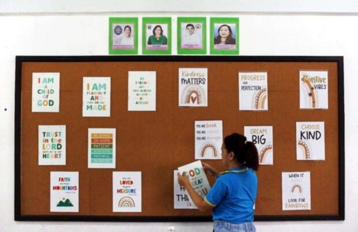 A Grade 2 teacher starts removing laminated posters with inspirational lines that she made for her students at the Pasig Central Elementary School during Brigada Eskwela 2023. A recent Department of Education order requires the removal of wall decors, posters, and other decorations in classrooms and keep it plain to avoid visual distractions to students. PHOTO BY LYN RILLON, PHILIPPINE DAILY INQUIRER