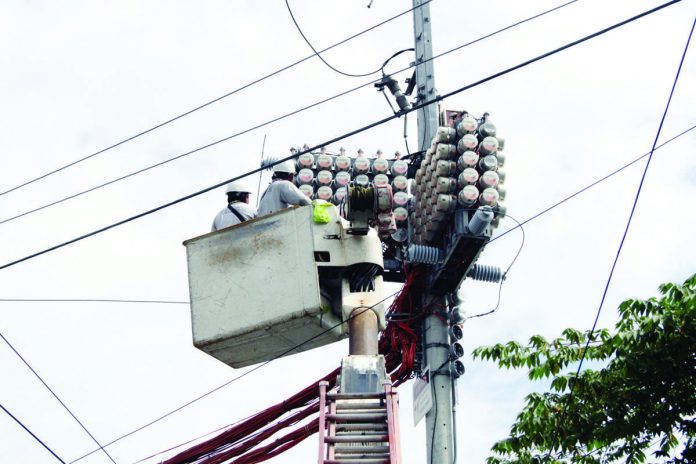 The government will begin rolling out this September its Lifeline Rate program that will aid low-income households pay their electricity bills. Photo shows Meralco personnel reading the numbers on the electric meters on a post on Padilla Street in Manila. PNA PHOTO BY JESS M. ESCAROS JR.