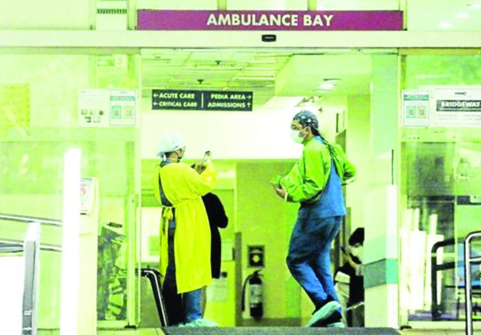 Emergency room personnel share a light moment at the ambulance bay of the Makati Medical Center. FILE PHOTO