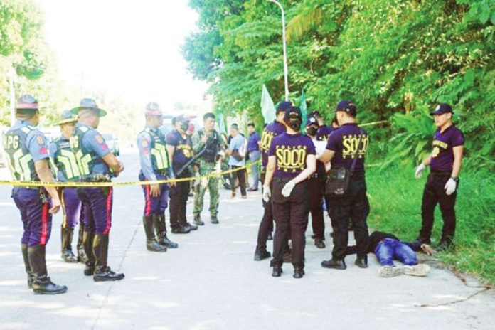 Police gather evidence beside bodies at the scene of a shooting outside a polling station following a confrontation between supporters of rival candidates, during the nationwide village and youth representative elections in Datu Odin Sinsuat town on Mindanao island on Oct. 30, 2023. Photo by Ferdinandh CABRERA / AFP