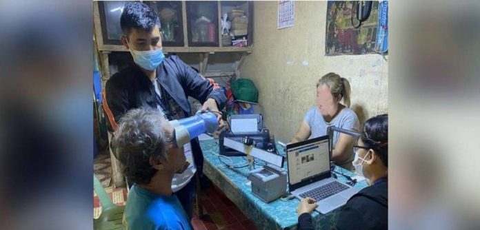 A senior citizen of Guimaras has his eyes scanned for his national ID. A personnel of the Philippine Statistics Authority is assisting him. PSA-GUIMARAS