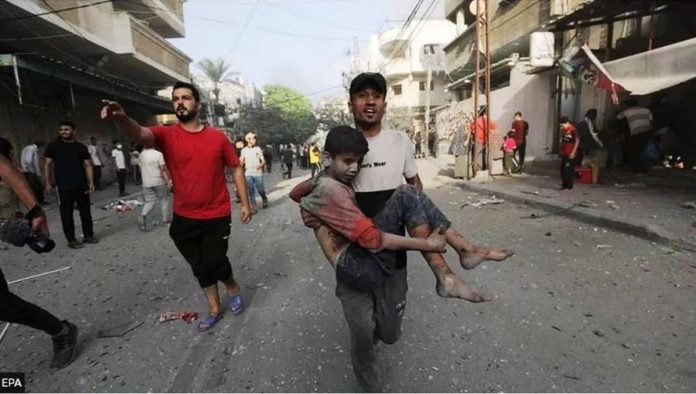 A Palestinian man carries a wounded boy following an Israeli air strike in northern Gaza. EPA