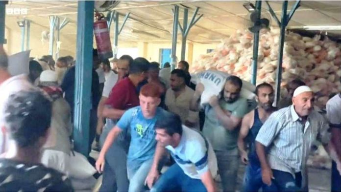 There is chaos at this Gaza Strip aid center as people grab supplies after a break-in. BBC