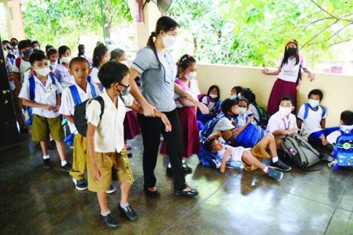 A teacher guides her students before a nationwide earthquake drill, at the Rafael Palma Elementary School in Manila. FILE PHOTO BY TED ALJIBE / AFP