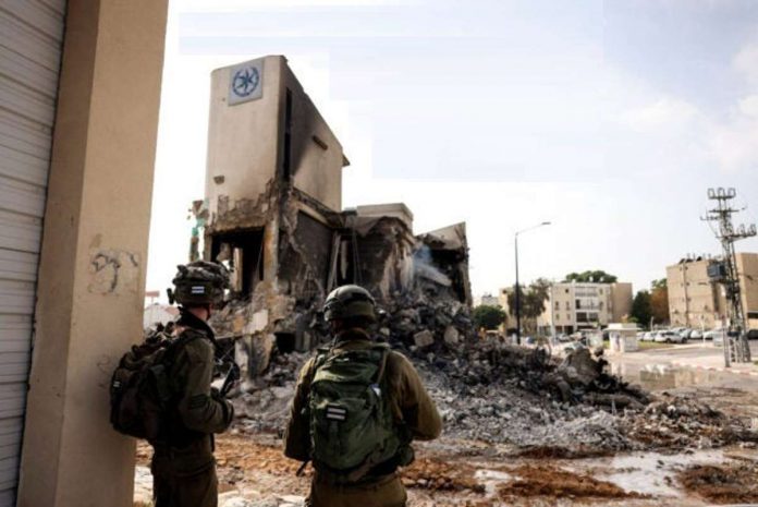 Israeli soldiers look at the remains of a police station which was the site of a battle following a mass infiltration by Hamas gunmen from the Gaza Strip, in Sderot, southern Israel on Oct., 2023. REUTERS