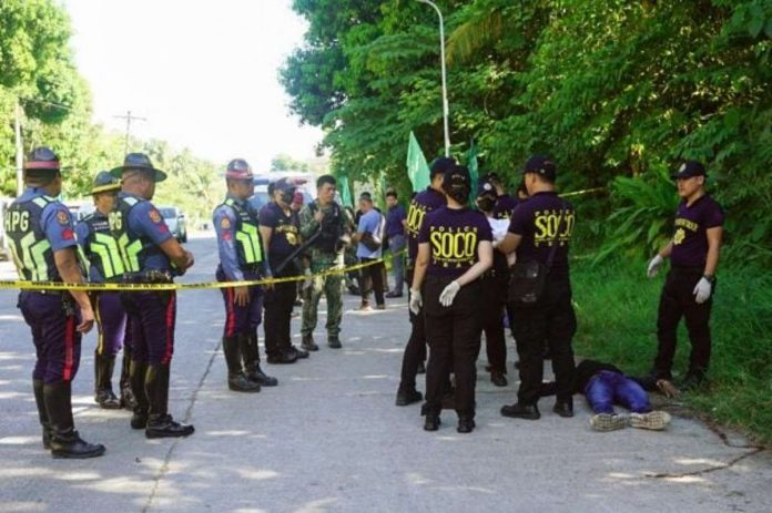 Police gather evidence beside bodies at the scene of a shooting outside a polling station following a confrontation between supporters of rival candidates, during the nationwide village and youth representative elections in Datu Odin Sinsuat town on Mindanao island on Oct.30, 2023. PHOTO BY FERDINANDH CABRERA / AFP