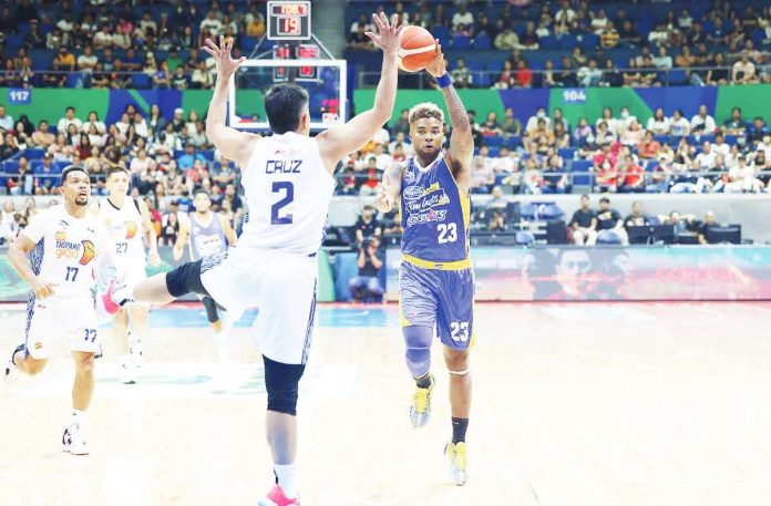 Magnolia Chicken Timplados Hotshots’ Joseph Eriobu looks to pass the ball after being bothered by the defense of TNT Tropang Giga’s Carl Bryan Cruz. PBA PHOTO