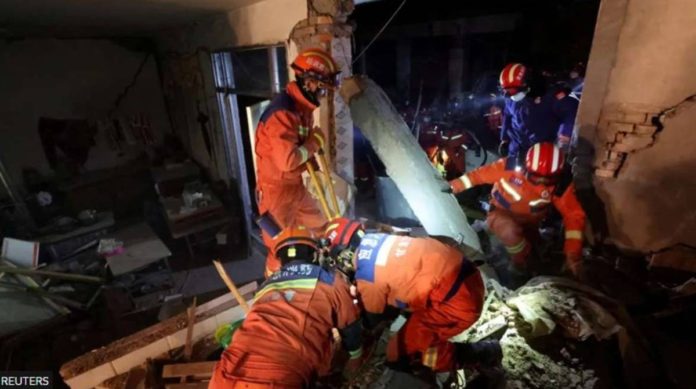 Rescuers in orange outfits checked this earthquake-damaged building in Kangdiao village in Jishishan county. REUTERS